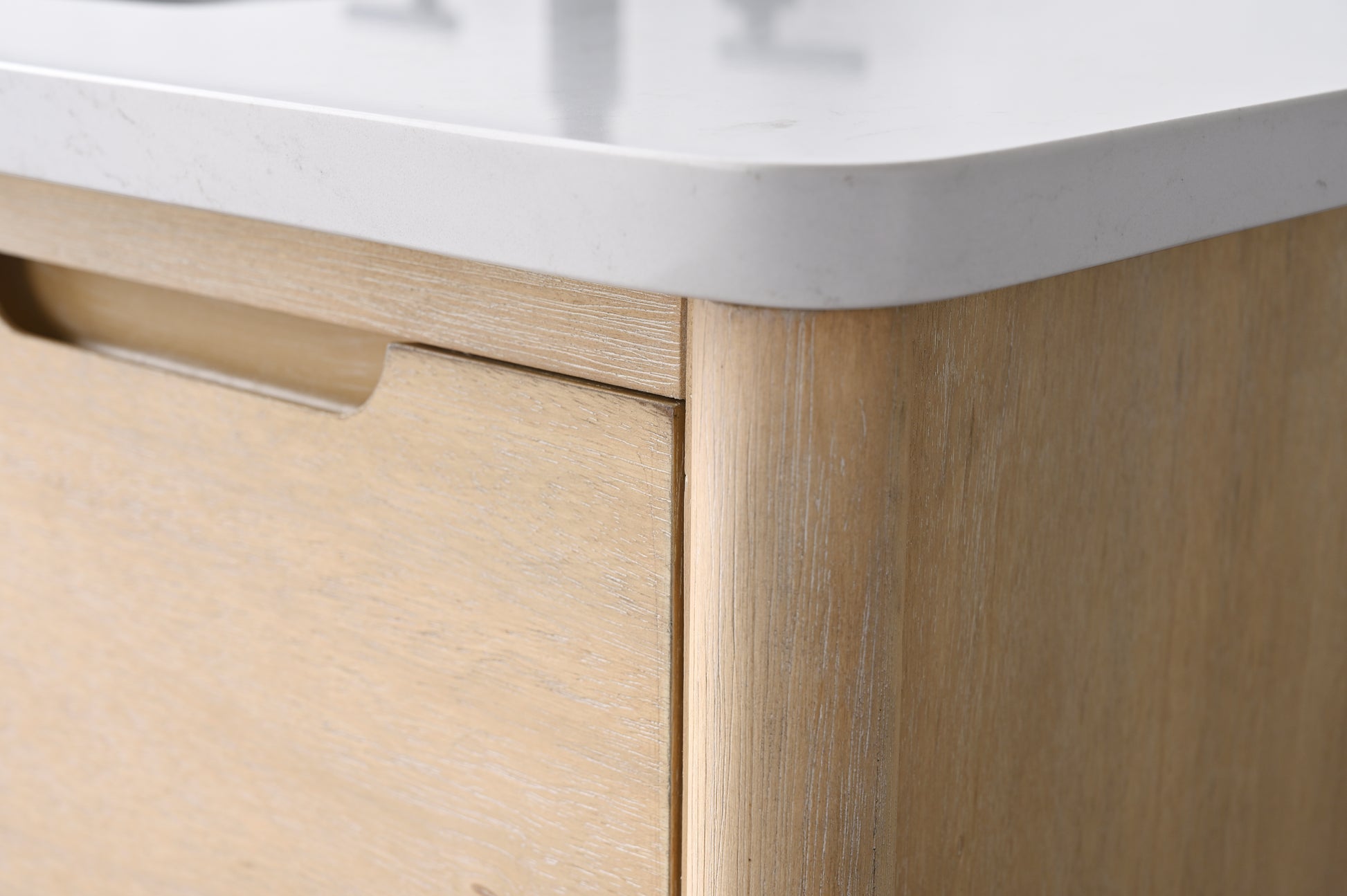 Close-up of VanityArt vanity cabinet corner showing light oak wood grain finish and white engineered stone countertop edge