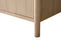 Close-up of bottom corner of light oak bathroom vanity showing tapered round leg and vertical wood grain