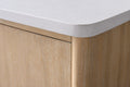 Close-up of white engineered stone countertop corner resting on light oak vanity cabinet side panel