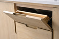 Close-up of tilt-out vanity drawer open revealing angled wooden interior tray with finger-pull handle