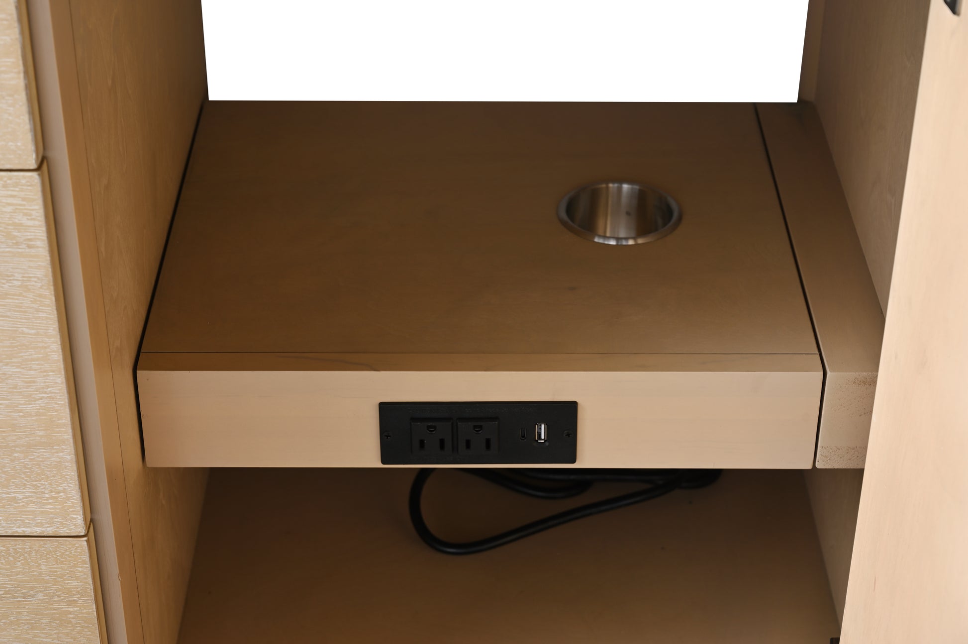 Pull-out shelf inside vanity cabinet with built-in power outlet USB port and stainless steel cord grommet